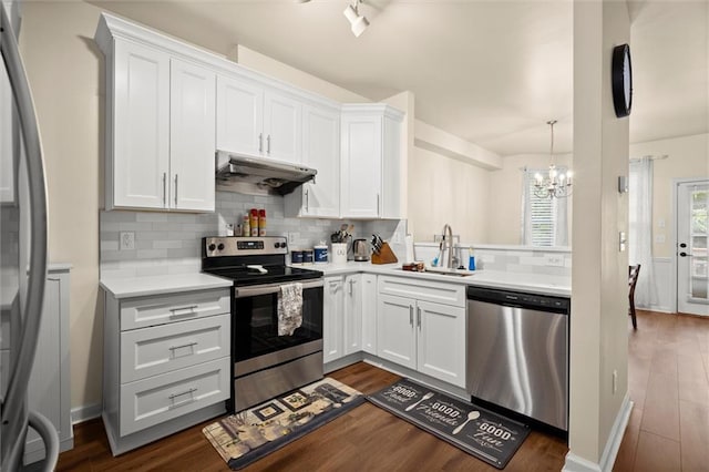 kitchen with appliances with stainless steel finishes, under cabinet range hood, a sink, a chandelier, and light countertops
