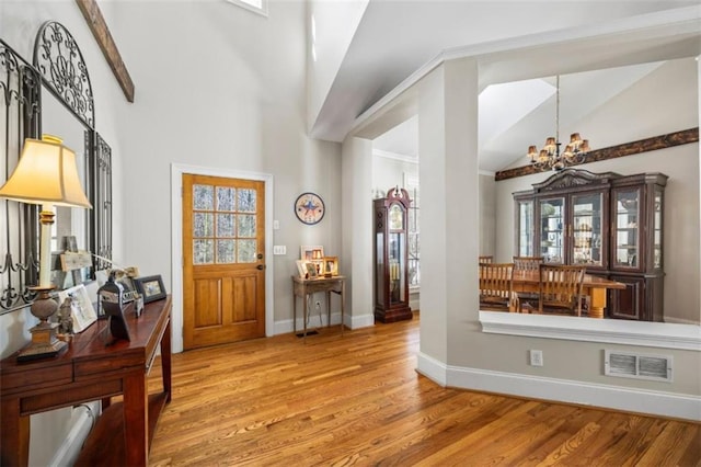 entrance foyer with a notable chandelier, wood-type flooring, and high vaulted ceiling