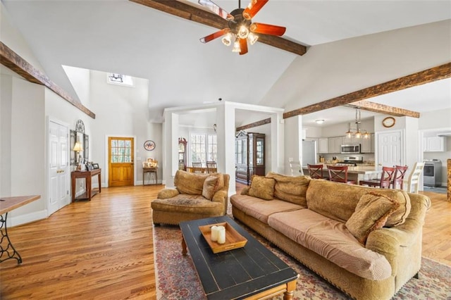 living room with beam ceiling, ceiling fan with notable chandelier, high vaulted ceiling, and light wood-type flooring