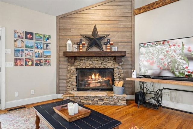 living room with wood-type flooring and a stone fireplace