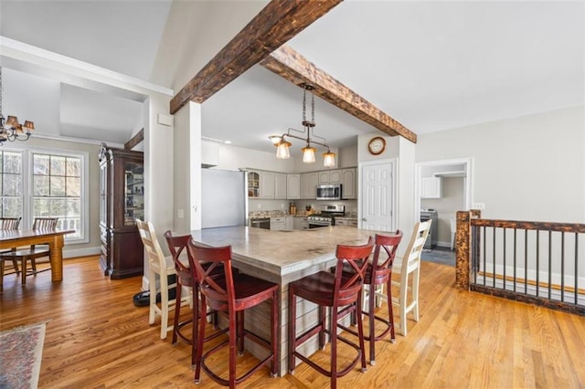 dining area with beamed ceiling, a notable chandelier, and light hardwood / wood-style floors