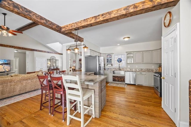 kitchen featuring sink, gray cabinets, appliances with stainless steel finishes, light hardwood / wood-style floors, and a kitchen bar