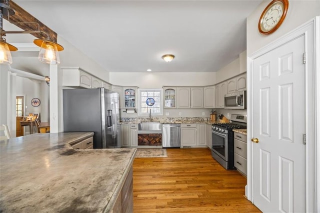 kitchen with sink, wood-type flooring, decorative light fixtures, gray cabinets, and stainless steel appliances