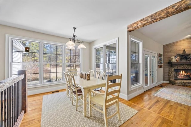 dining area with a stone fireplace, light hardwood / wood-style flooring, and a wealth of natural light