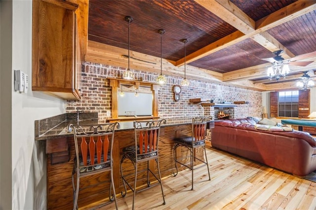 bar with light hardwood / wood-style flooring, wooden ceiling, beamed ceiling, ceiling fan, and brick wall