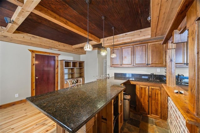 kitchen with wood ceiling, beamed ceiling, decorative light fixtures, kitchen peninsula, and dark stone counters