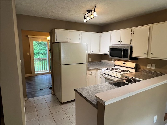 2705 Rhoanoke Dr, Duluth, GA 30096 - kitchen featuring a peninsula, white appliances, white cabinetry, a sink, and light tile patterned floors