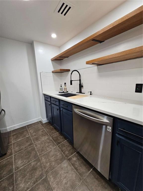 kitchen with stainless steel dishwasher, blue cabinets, sink, and backsplash