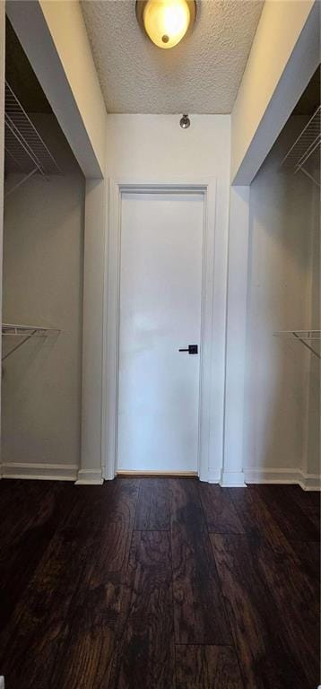 corridor featuring dark hardwood / wood-style flooring and a textured ceiling