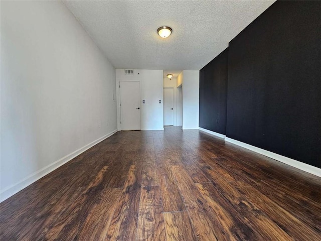 unfurnished room featuring dark wood-type flooring and a textured ceiling