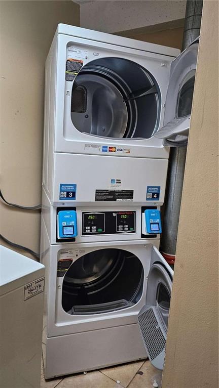 laundry room featuring stacked washer / drying machine and light tile patterned floors