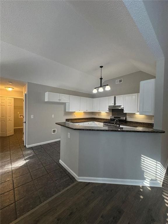 12 Barrington Ct, Sharpsburg, GA 30277 - kitchen with dark countertops, vaulted ceiling, white cabinets, a peninsula, and pendant lighting