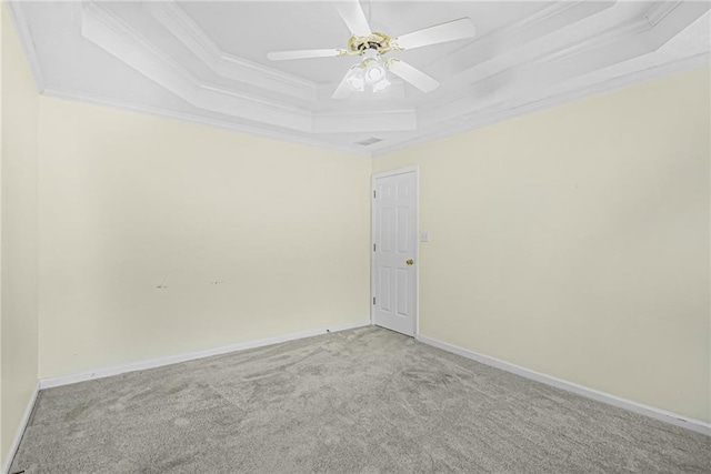 spare room with light carpet, a ceiling fan, baseboards, a raised ceiling, and crown molding