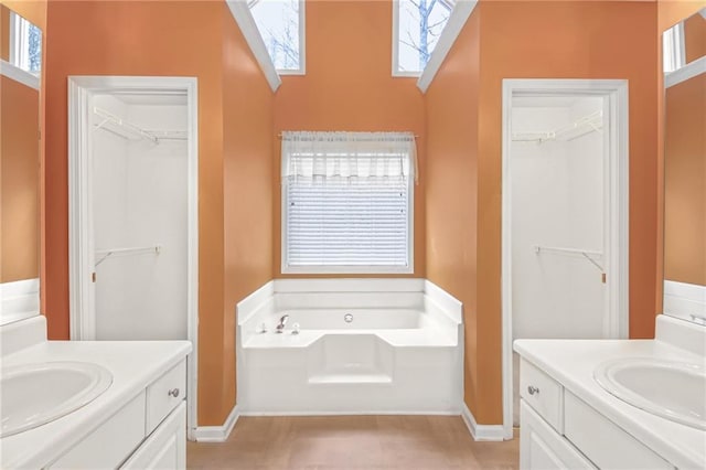 full bath featuring two vanities, a sink, and a bath