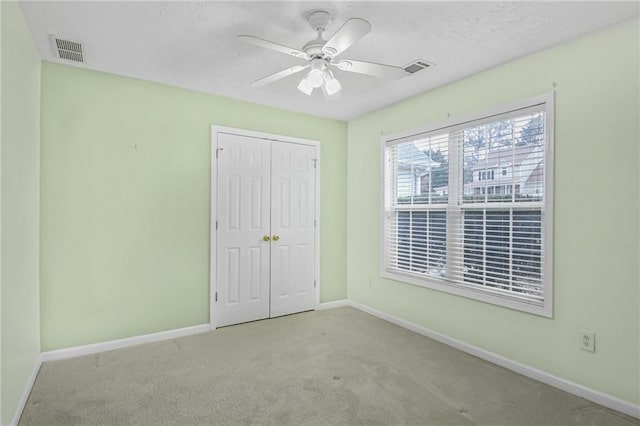 unfurnished bedroom featuring a closet, carpet, visible vents, and baseboards