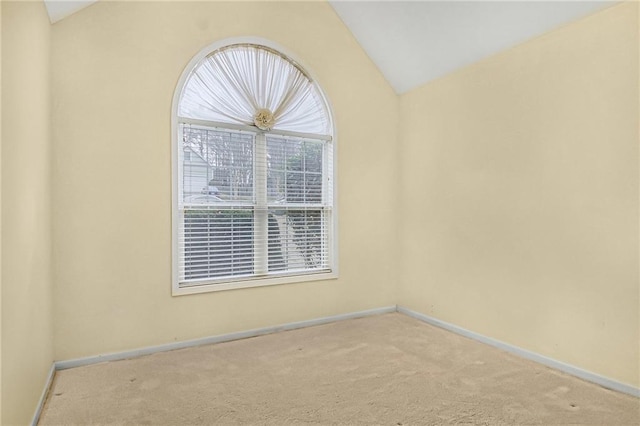 spare room with baseboards, vaulted ceiling, and carpet flooring