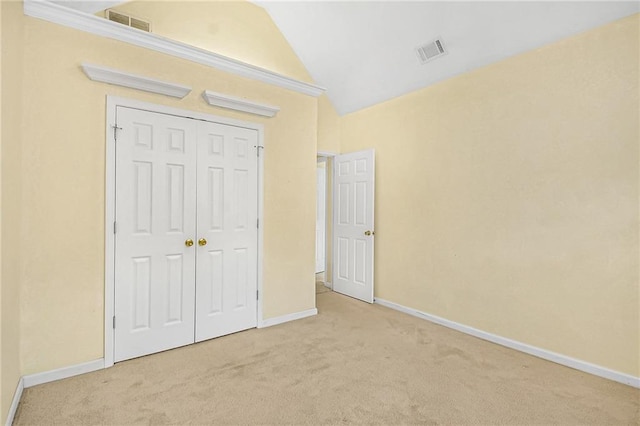 unfurnished bedroom featuring baseboards, visible vents, vaulted ceiling, and carpet flooring