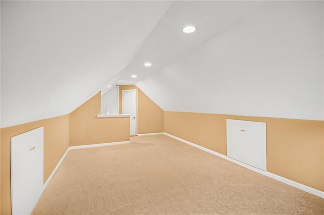 additional living space with baseboards, vaulted ceiling, and light colored carpet