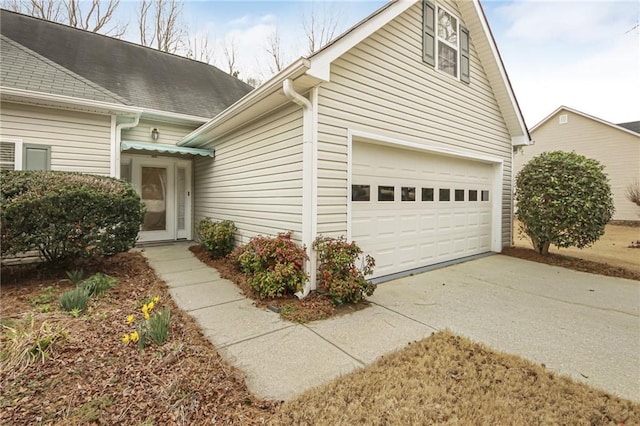 view of front of home featuring a garage, concrete driveway, and a shingled roof