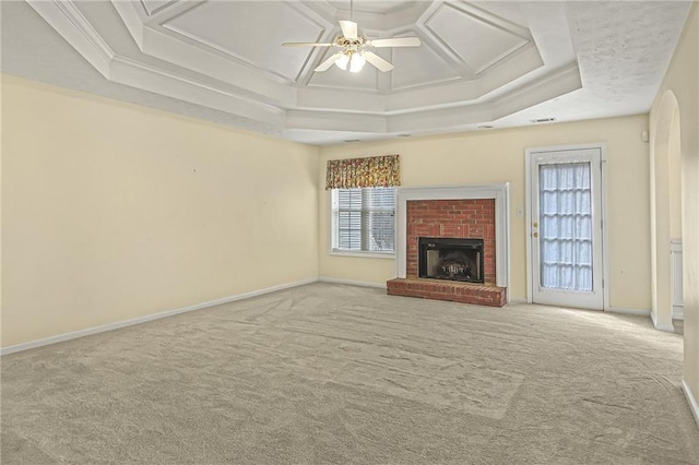 unfurnished living room with ceiling fan, a fireplace, a raised ceiling, and baseboards