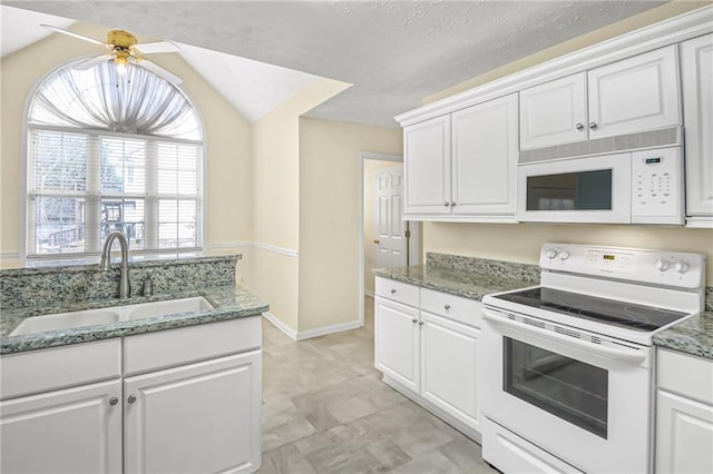 kitchen with white appliances, a sink, light stone counters, and white cabinets