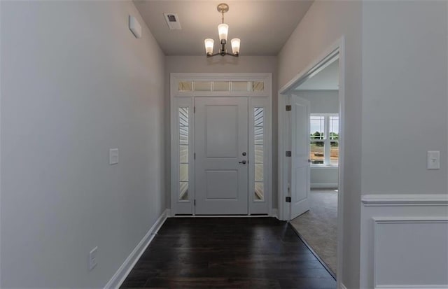 foyer featuring dark wood-style floors, a notable chandelier, visible vents, and baseboards