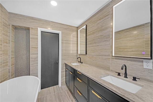 bathroom with vanity, a bathtub, tile patterned floors, and tile walls