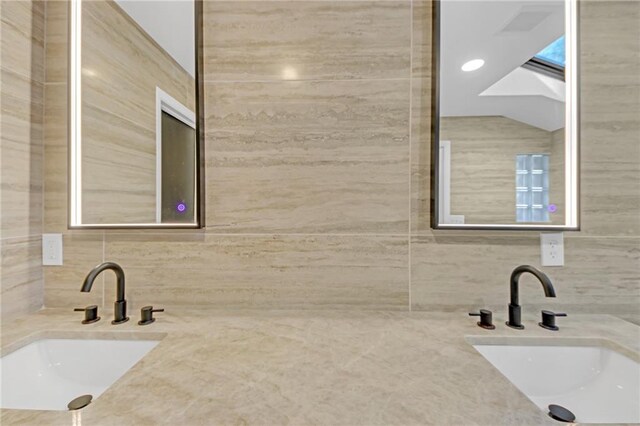 bathroom featuring vanity and tile walls