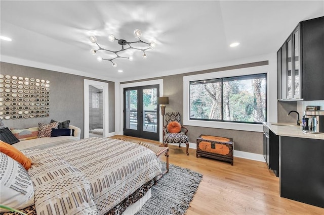 bedroom with access to exterior, french doors, light hardwood / wood-style flooring, and sink