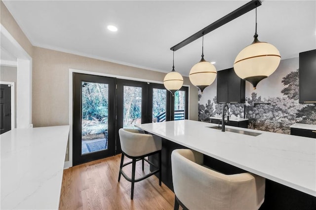 dining room with light hardwood / wood-style floors, crown molding, sink, and french doors