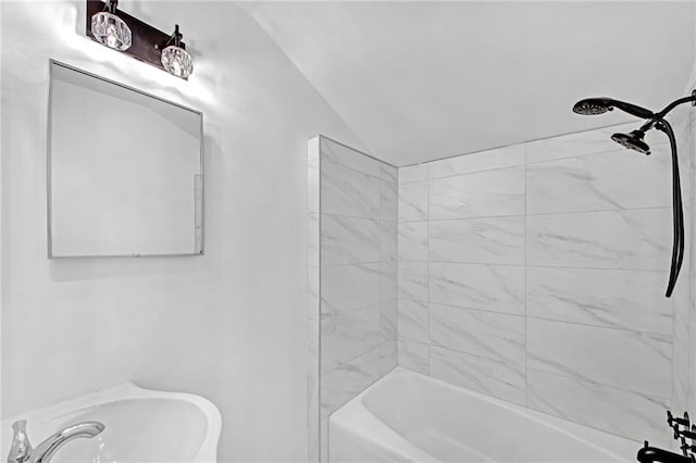 bathroom with tiled shower / bath combo and vaulted ceiling