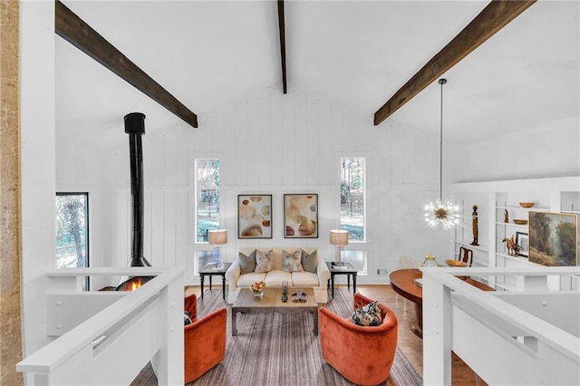 living room featuring hardwood / wood-style floors, lofted ceiling with beams, a wood stove, and a chandelier