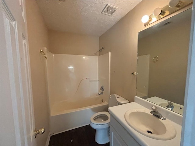 full bathroom with vanity, toilet, tub / shower combination, and a textured ceiling