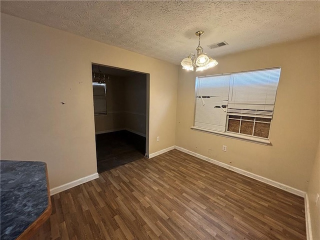 unfurnished room with dark hardwood / wood-style floors, a notable chandelier, and a textured ceiling