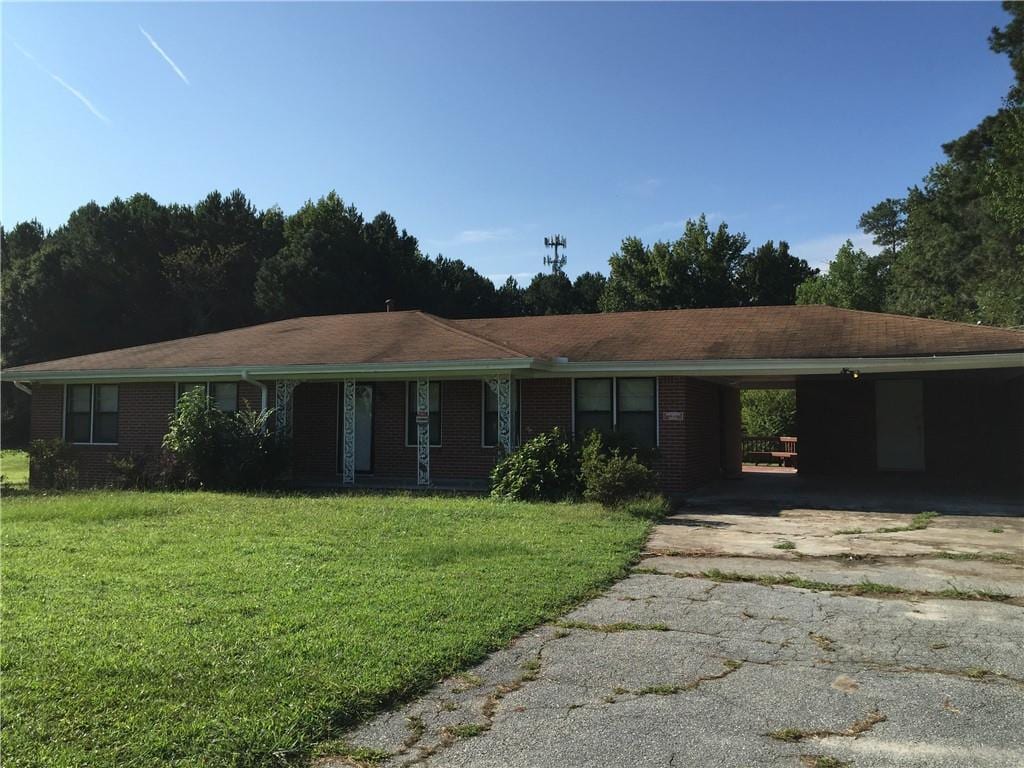 ranch-style home with a carport and a front lawn