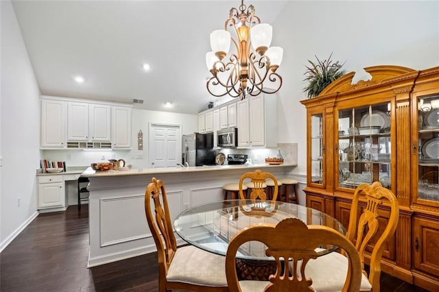 dining room featuring vaulted ceiling, dark hardwood / wood-style flooring, and an inviting chandelier