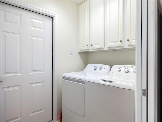 laundry room featuring washer and clothes dryer and cabinets