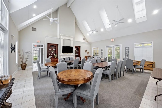 dining area featuring ceiling fan, light tile patterned floors, high vaulted ceiling, and a skylight