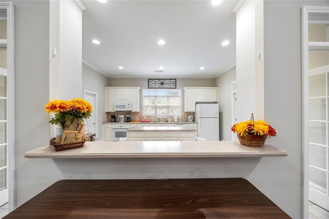 kitchen featuring white appliances, white cabinets, sink, tasteful backsplash, and kitchen peninsula