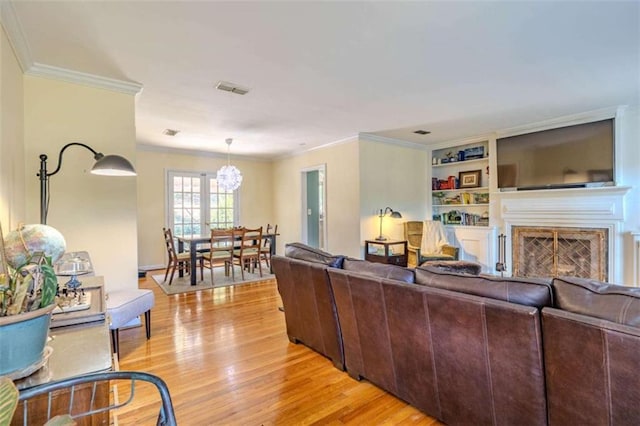 living room featuring crown molding, an inviting chandelier, and light wood-type flooring