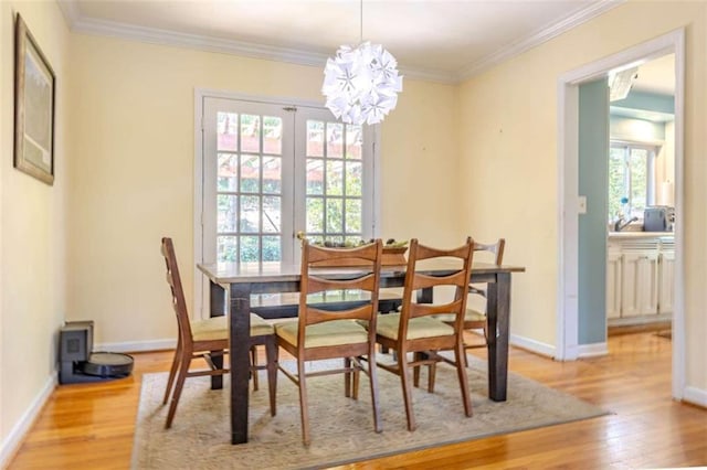 dining space featuring ornamental molding, an inviting chandelier, light wood-type flooring, and french doors