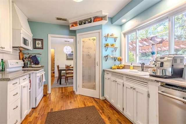 kitchen with sink, white cabinets, white appliances, and light hardwood / wood-style flooring