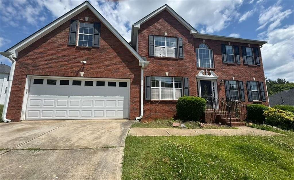 colonial inspired home with concrete driveway, brick siding, a garage, and a front lawn