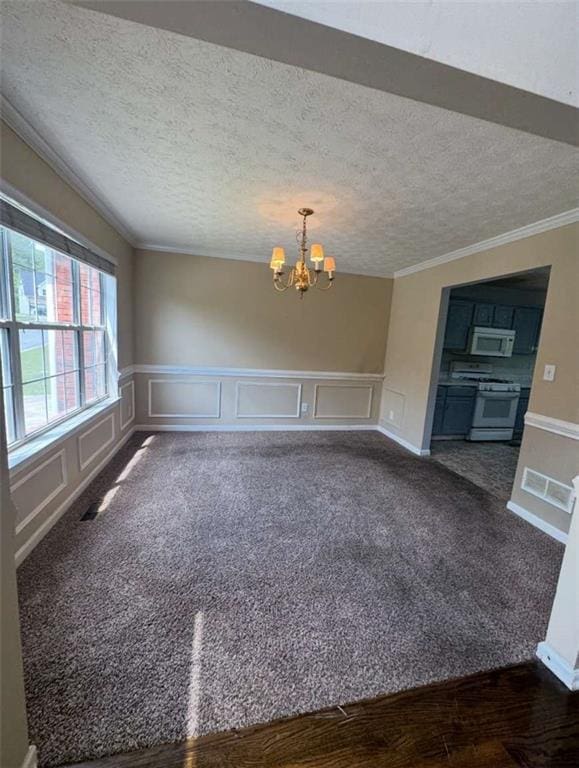 unfurnished room featuring a textured ceiling, ornamental molding, a chandelier, a decorative wall, and dark carpet