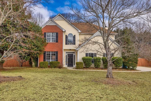 traditional-style house with a front lawn, fence, and brick siding