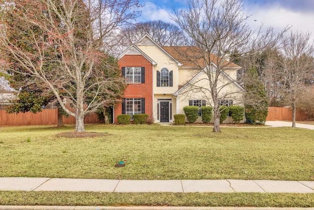 traditional-style home with brick siding, a front yard, and fence