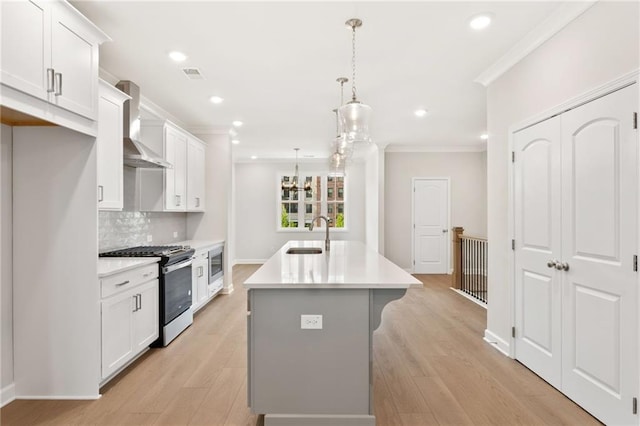 1987 Deco Dr, Kennesaw, GA 30144 - kitchen featuring appliances with stainless steel finishes, wall chimney exhaust hood, ornamental molding, a center island with sink, and light countertops