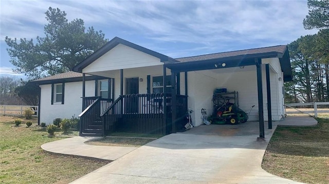 view of front of property featuring covered porch, concrete driveway, a carport, and fence