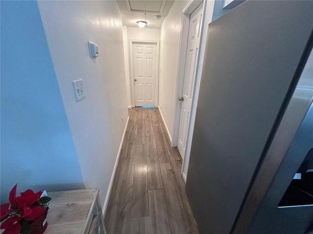 hall with wood finished floors, attic access, and baseboards