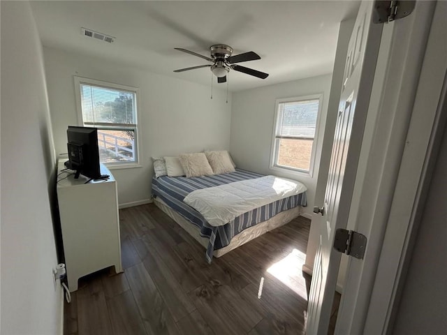 bedroom with ceiling fan, multiple windows, wood finished floors, and visible vents